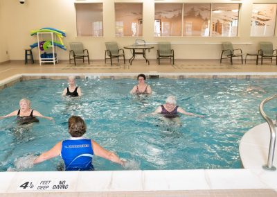 residents on hydroriders in pool with trainer in pool
