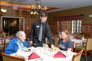 resident and family being served lunch by waiter