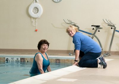 rehab specialist with resident talking at the pool