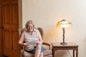 avila resident reading in a sitting chair with lighted lamp