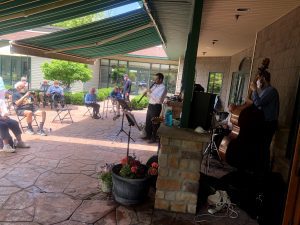 Retirees enjoying live entertainment outside practicing social distancing